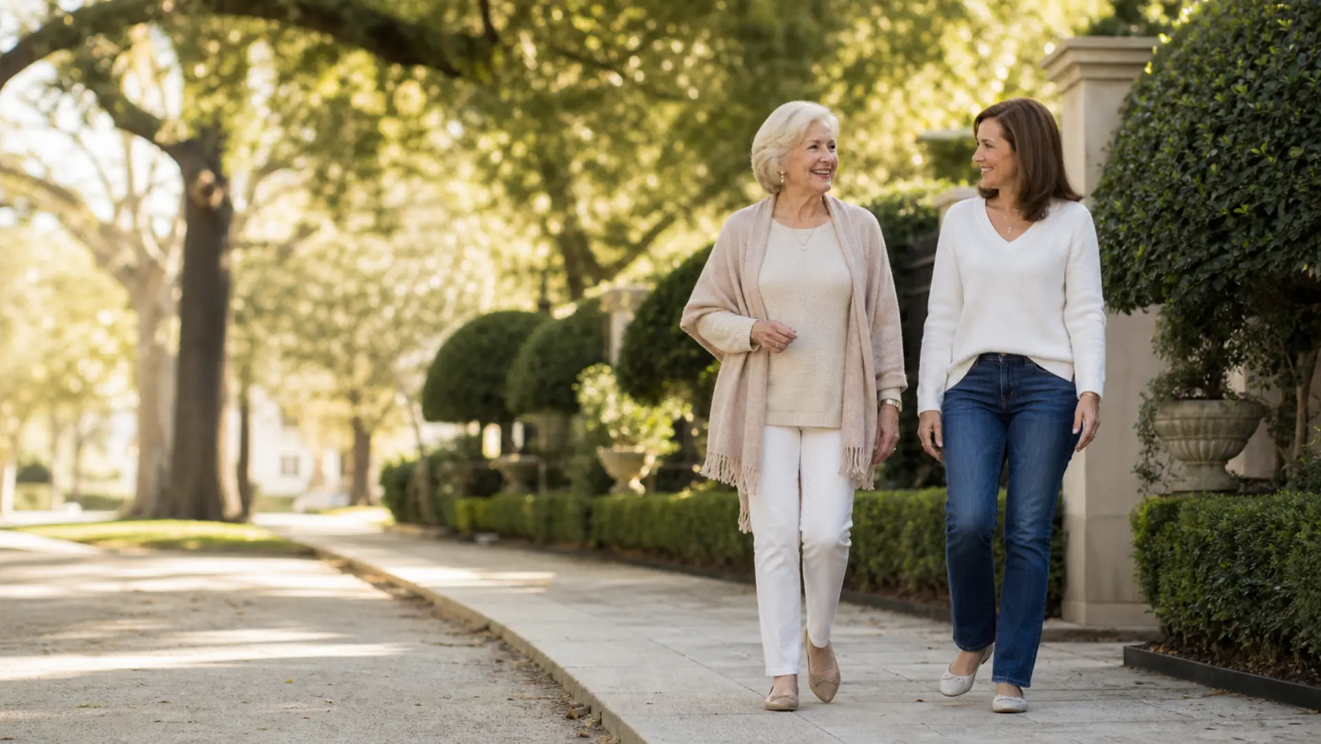 An older adult and a companion walking a shaded street together